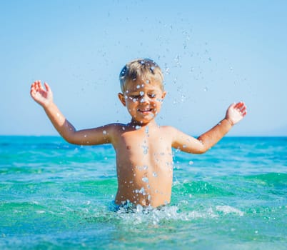 Portrait of young boy swimming and squirting in the transparent sea