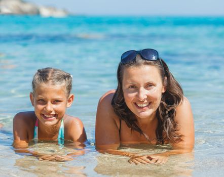 Portrait of cute girl swimming with her mother in the transparent sea