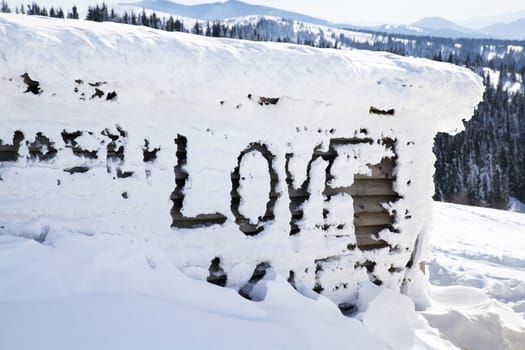 Word Love on the wall written on the snow