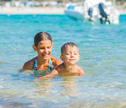 Happy kids. Sister and brother playing and swimming in the transparent sea