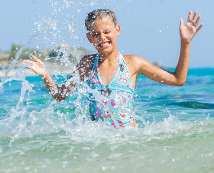 Portrait of cute girl swimming and squirting in the transparent sea