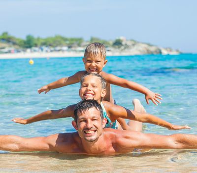 Family - father with his kids have fun and swim in the transparent sea