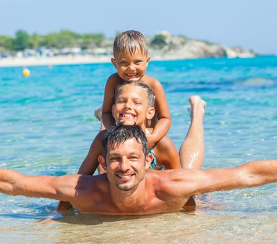 Family - father with his kids have fun and swim in the transparent sea