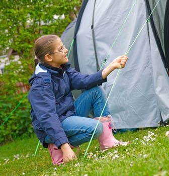 Young girl out camping learning how to pitch tent