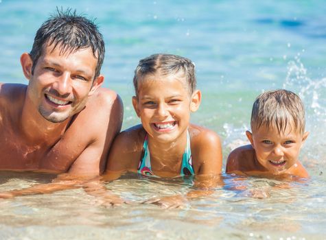 Family - father with his kids have fun and swim in the transparent sea