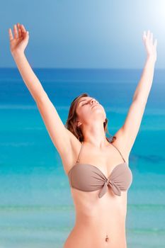 Woman stretching at the beach with the ocean behind