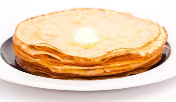 Golden pancakes on white plate with butter