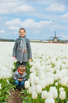 Boy with his sister runs between of the purple tulips field. Vertical view