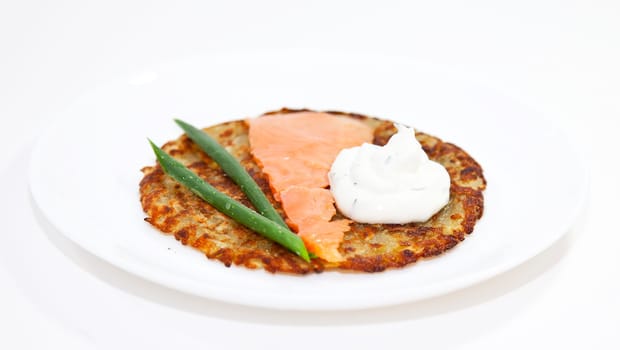 Rosti with salmon and sour cream on the white plate