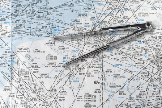 A pair of compasses resting on an aeronautical navigational chart