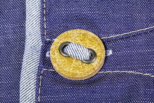 Yellow button on jeans texture close view