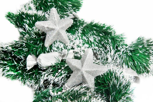 Christmas shiny stars on green tinsel on white background