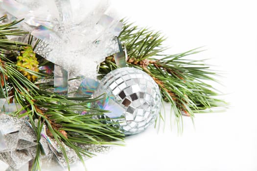 Fir tree branch with Christmas ball and shiny tinsel on white background