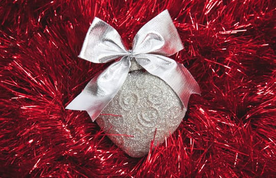 Silver Christmas heart on red tinsel background