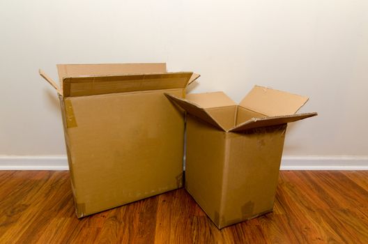 Moving day with empty cardboard boxes on hardwood floor.