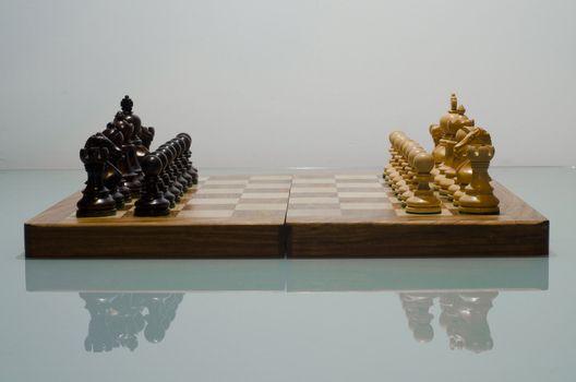 chessboard with pieces set up for play shoot on reflective surface in studio