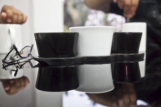 horizontal generic angled abstract in a cafeteria of a asian couple sat having a beverage, black reflective table top, highlights, spectacles coffee mugs and table utensils. Shot location, Goa, India