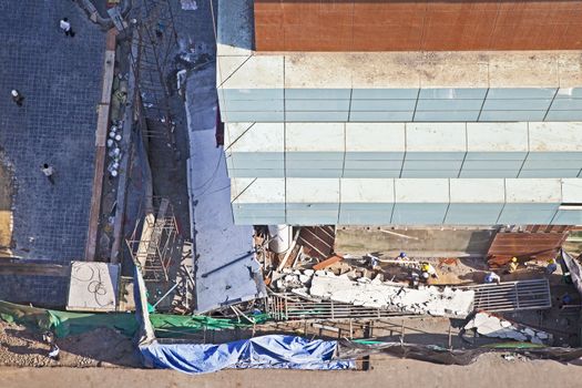 Horizontal aerial landscape of a new construction site where a section of a building has collapsed and work is going on about the clearing of the debris