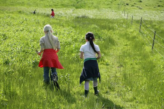 2  girls  running in a green field in spring