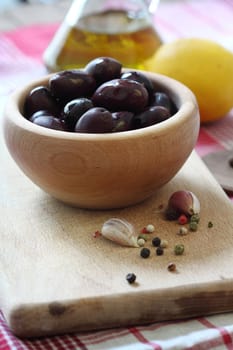 Black olives in wooden bowl close up, shallow dof