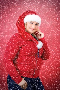 Joyful pretty woman in red santa claus hat smiling on red background