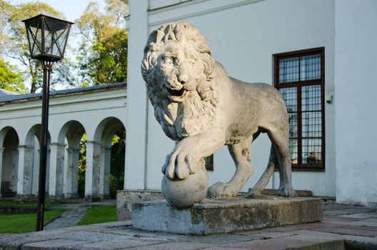 Retro stone lion sunlight with sun in park hold round ball with claw.