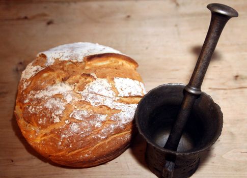 Old iron mortar next to newly baked peasant bread