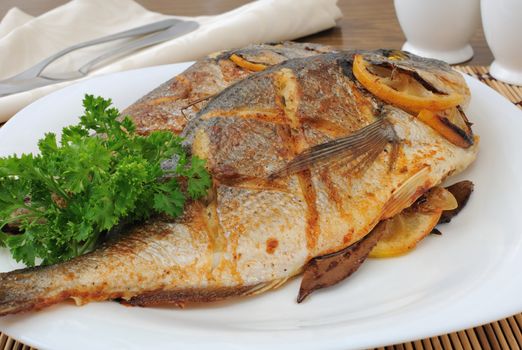 Dorado baked fish with lemon on a plate close-up