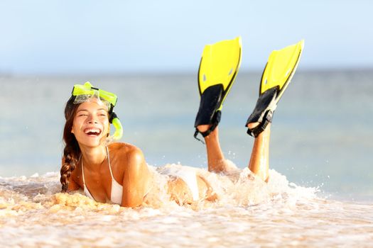 Water snorkeling fun beach woman laughing lying in sand cheerful with fins and mask. Beautiful young multicultural Asian / Caucasian woman.