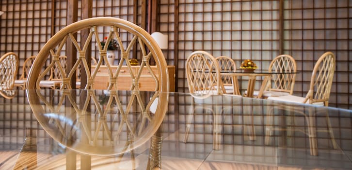 Glass table with wickler chairs in an elegant interior