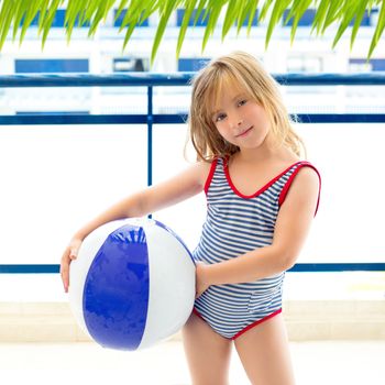 Blond kid girl with swimsuit with summer blue ball in balconade