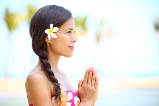 Serene meditation - meditating woman on beach smiling happy in profile on hawaiian beach. Beautiful portrait of mixed race Asian / Caucasian female model relaxing on Hawaii.