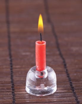Little red candle over wooden mat background