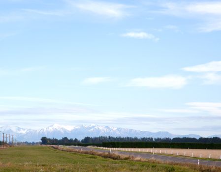 Long road stretching out into the distance with snow mountain background in New Zealand