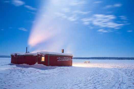 Winter landscape with cabin hut over frozen lake at night in Kiruna Sweden at Night with star trail