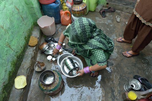 Indian woman washes dishes at his home in New Delhi