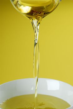 Pouring oil or golden liquid on yellow background