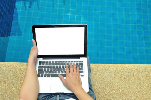 Man using laptop computer beside swimming pool in relax concept