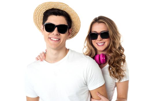 Dashing young couple wearing shades and hat isolated white.