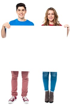 Full length portrait of young couple displaying blank white ad board.