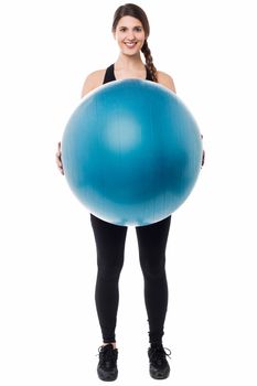 Active female gym instructor displaying a swiss ball.