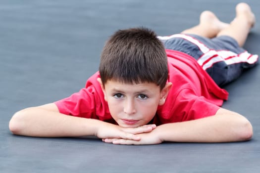 outdoor portrait of lying young teenager boy with shallow focus