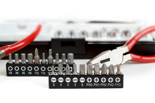 Screwdriver Bit Set on White with pliers shallow focus