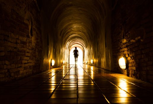 silhouette of human in old brick tunnel light at end of tunnel