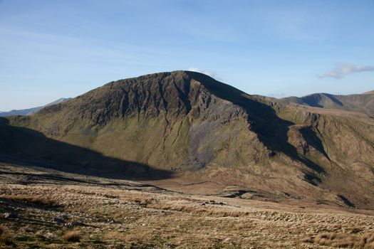 Grassland leads into a valley with the peak of Moel Cynghorian, Snowdonia national park, Wales, UK.