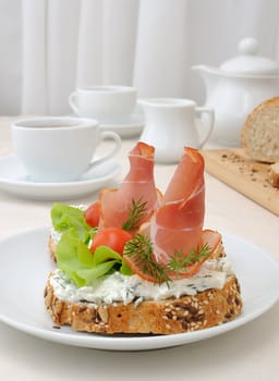 breakfast with a cup of coffee and a sandwich of whole grain bread with ricotta and ham