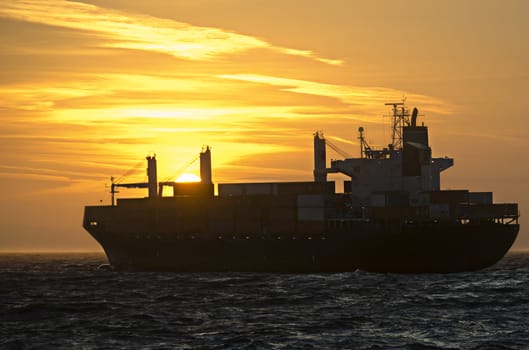 A container ship heading towards sunset on the german North Sea.