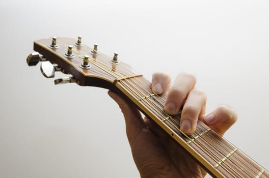 Neck of an acoustic guitar. A hand is holding the C major chord. White backgound.
