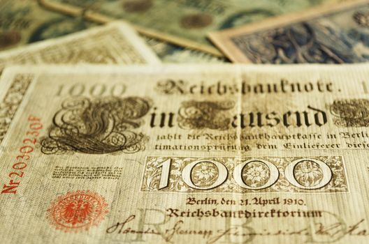Part of an old German banknote from 1910. Other old banknotes can be seen blurred in the background.