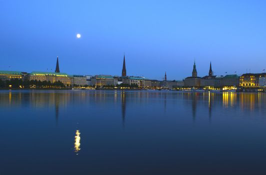Night shot of the Binnenalster in Hamburg. The full moon is reflected in the water.